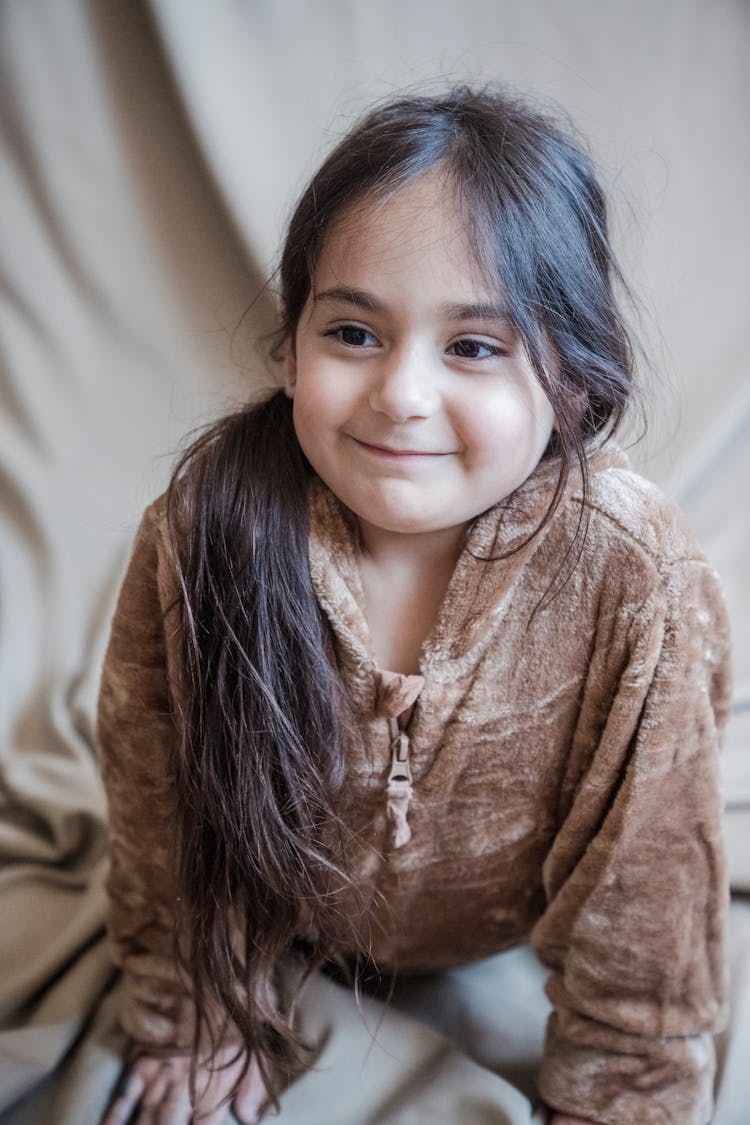 Girl In Brown Onesie Lying On Brown Textile