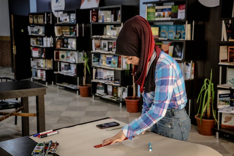 Woman In Library Preparing A Poster