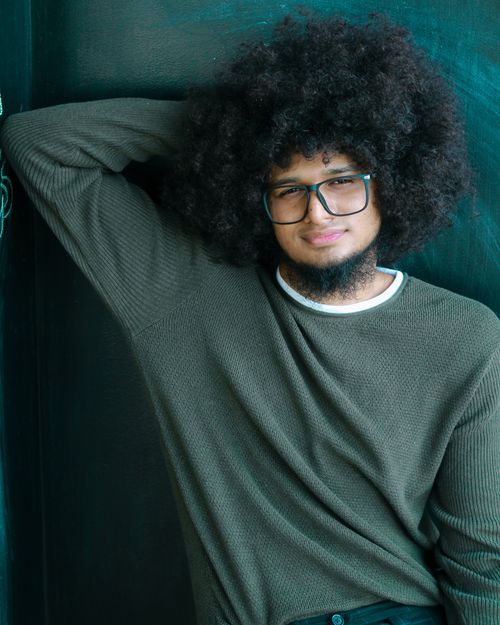 Free Stylish portrait of an African American man leaning casually with an afro and glasses. Stock Photo