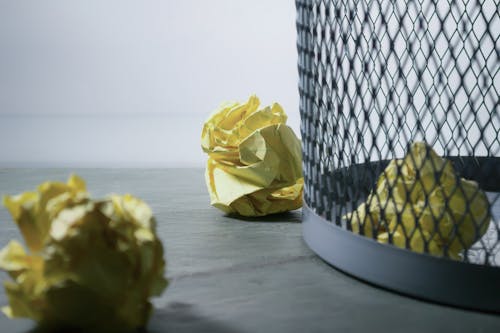 Foto Em Foco De Papel Amarelo Perto Da Lata De Lixo