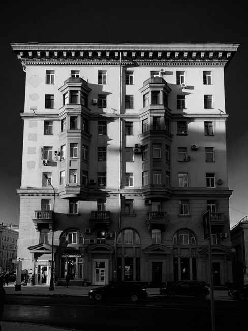 Bold black and white photo of an urban apartment building casting shadows.