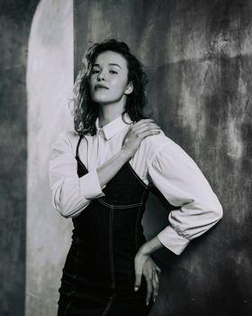 Fashionable woman in black and white portrait, wearing a denim dress and shirt.