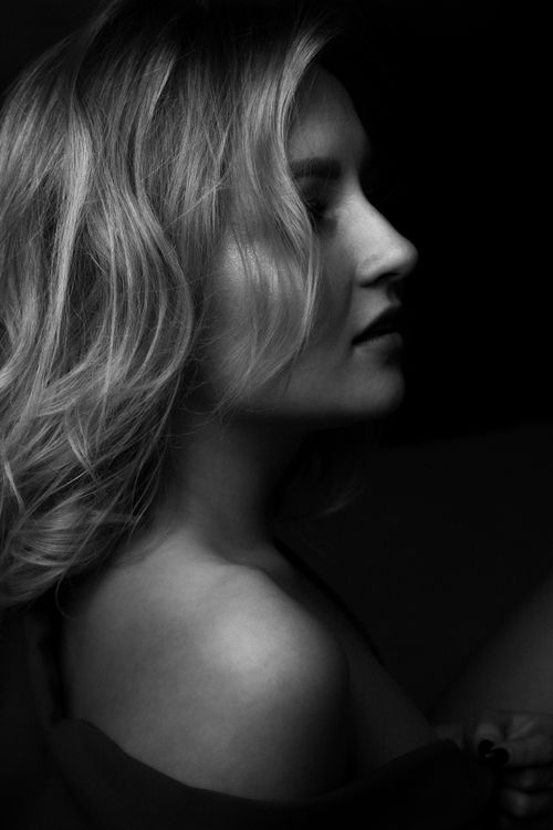 Free Artistic black and white side profile portrait of a woman in soft lighting. Stock Photo