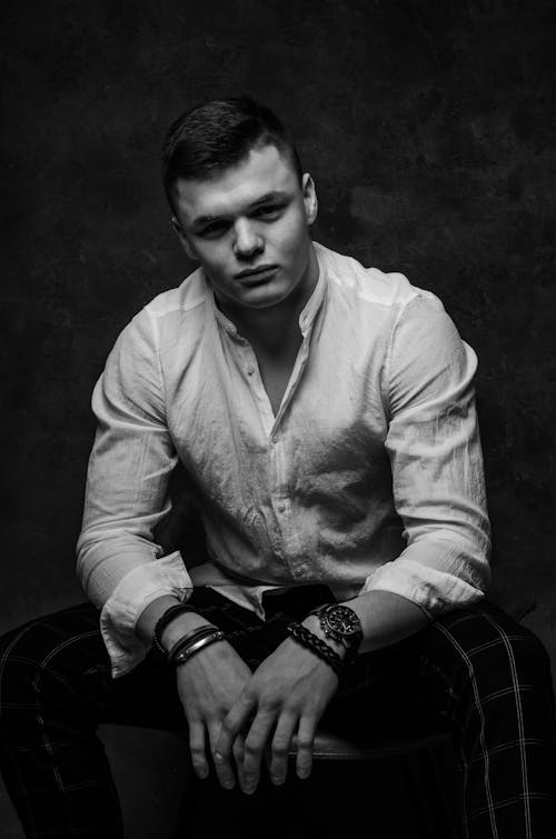 Grayscale Photo of a Man in White Long Sleeves Sitting