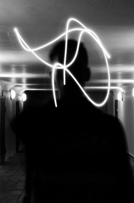 Creative silhouette in tunnel with striking light trails creating modern art effect.