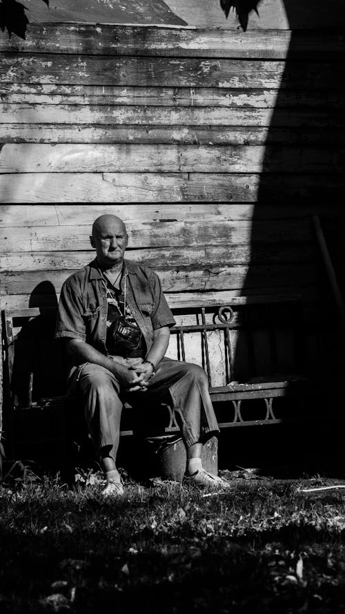 A Grayscale Photo of a Man Sitting on the Bench