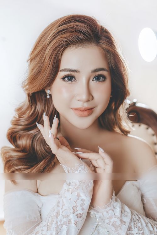 Free Glamorous portrait of a smiling woman with wavy hair and lace dress, exuding grace and confidence. Stock Photo