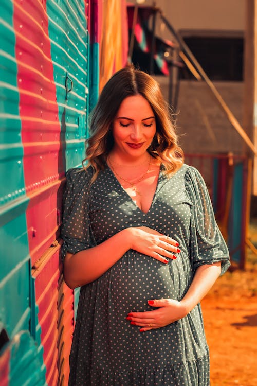 Free Pregnant Woman in Polka Dot Dress Touching her Baby Bump  Stock Photo