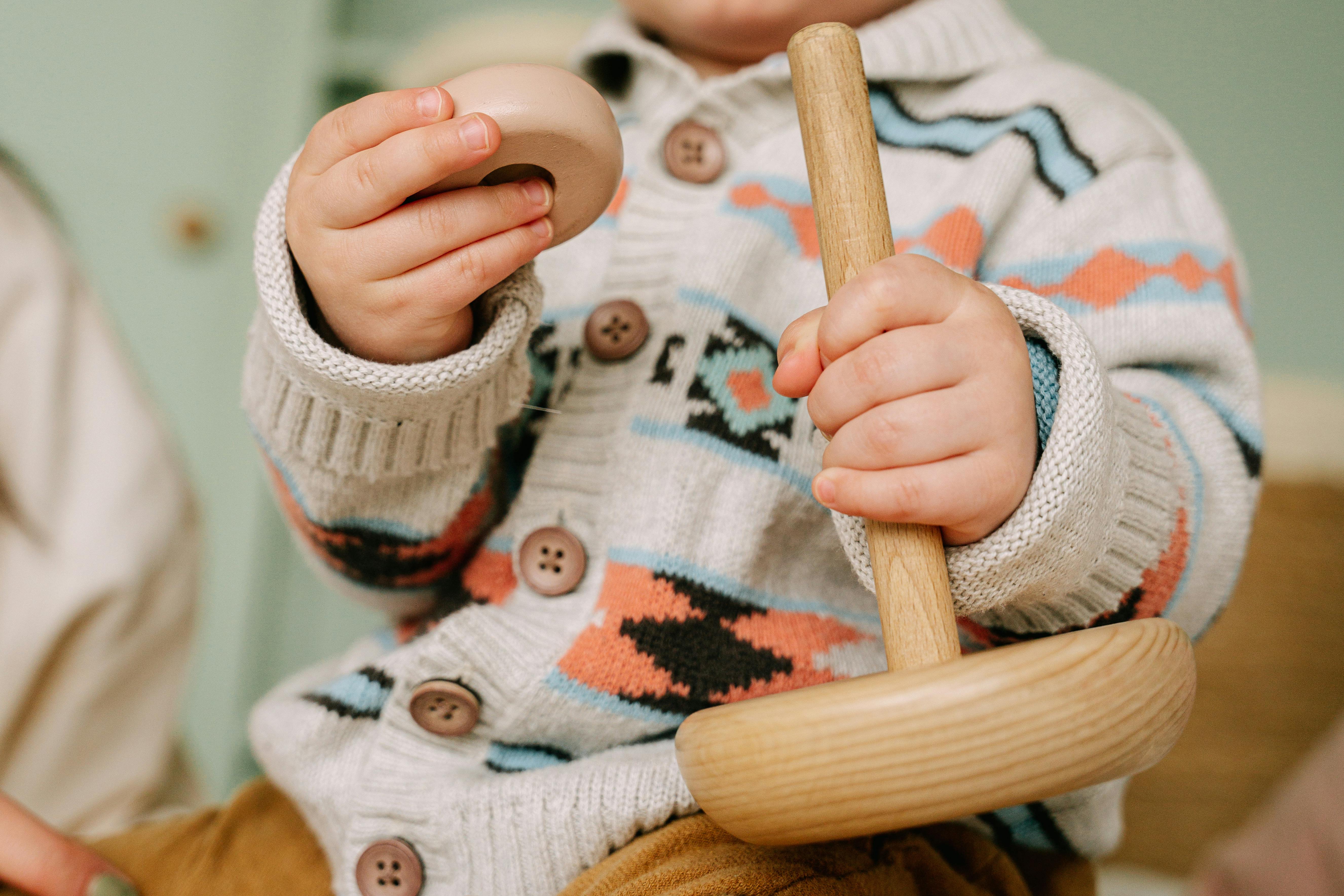 little boy holding a wooden toy