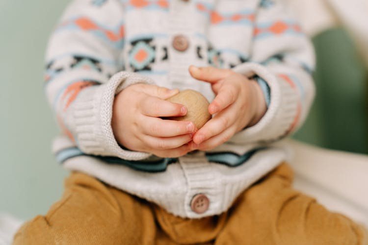 A Kid's Hands Holding A Wooden Ball