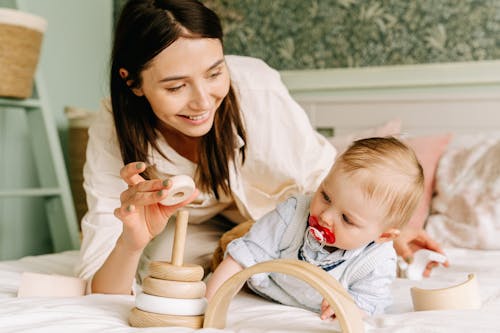 Free Mother and Baby Boy Playing with Wooden Toy Stock Photo