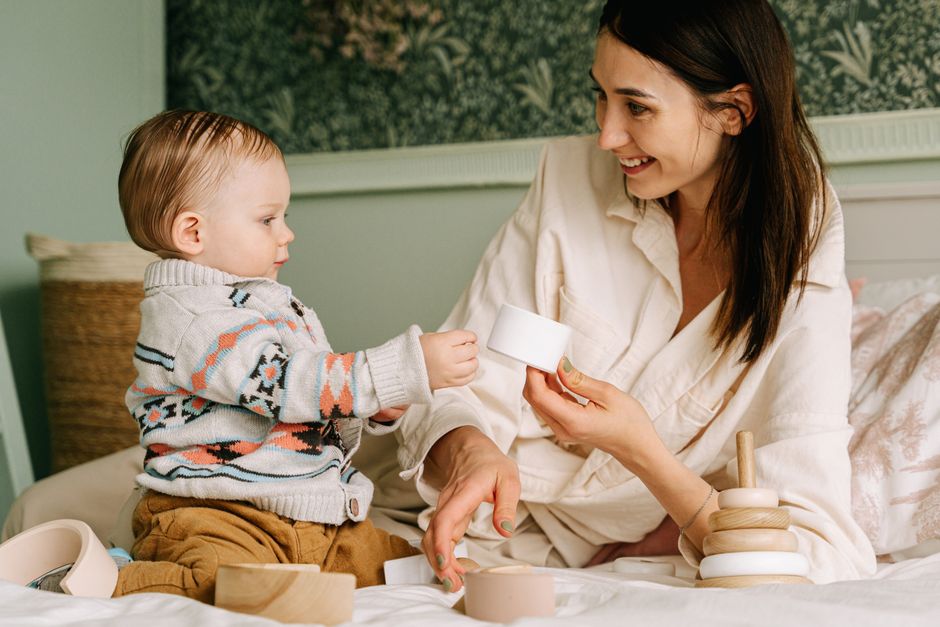 Photo by Ivan S on Pexels A mother and her child happily play with wooden toys on a cozy bed. - Photo by Ivan S on Pexels