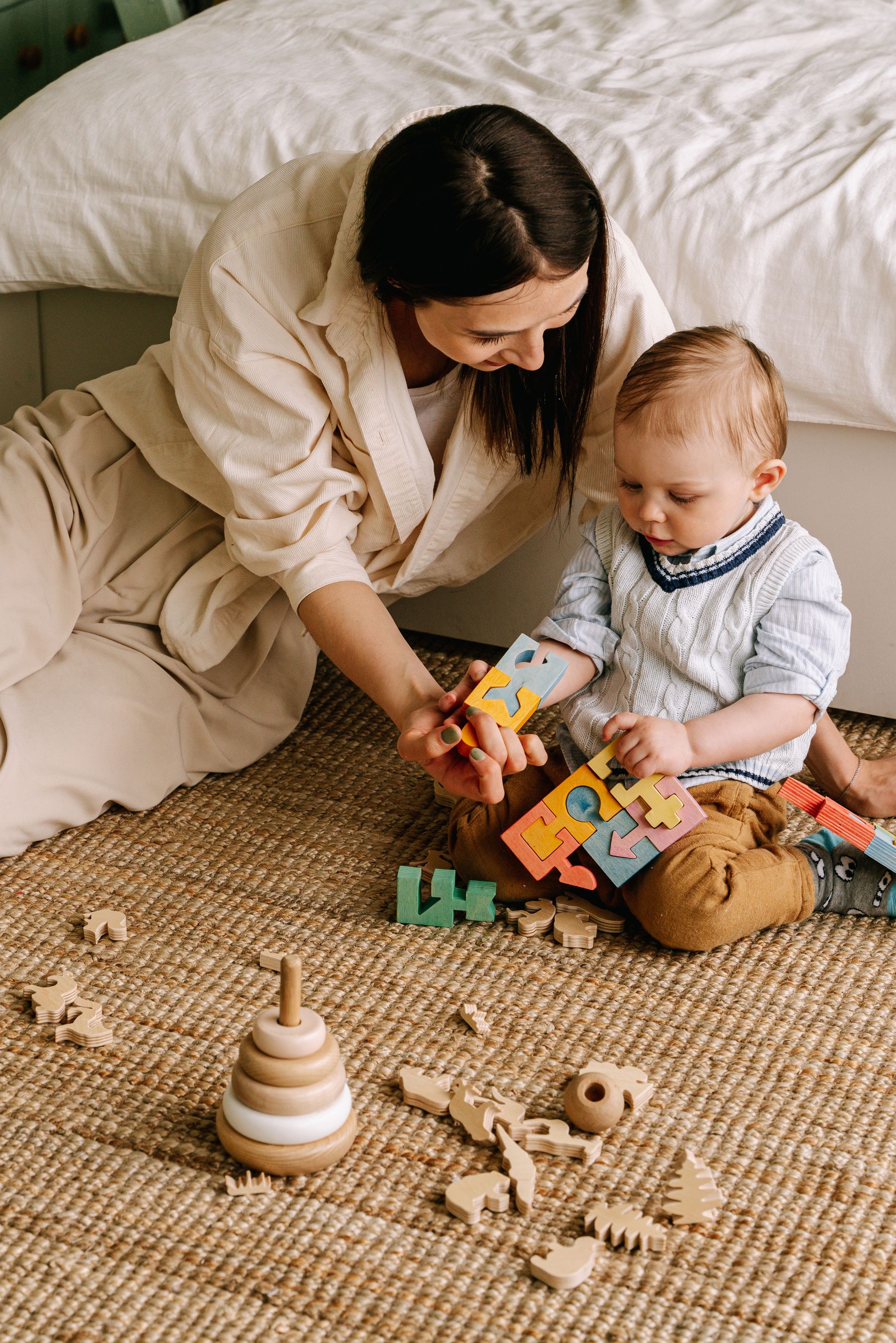 A mother and young child using a colorful wooden number puzzle together on a rug at home