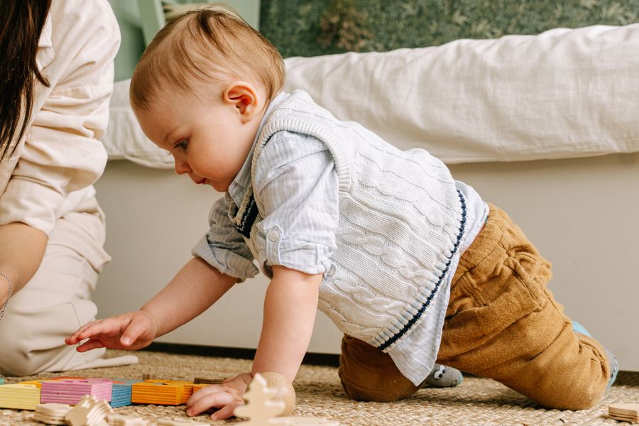 Baby boy playing with wooden blocks during early intervention