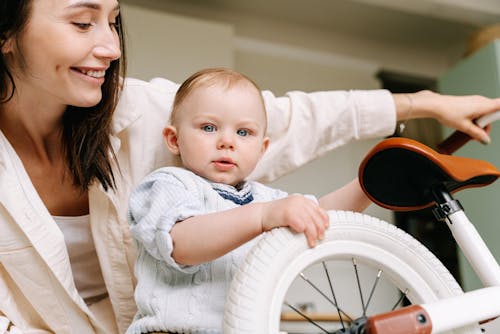 A Smiling Woman Looking at Her Son Near the Bicycle