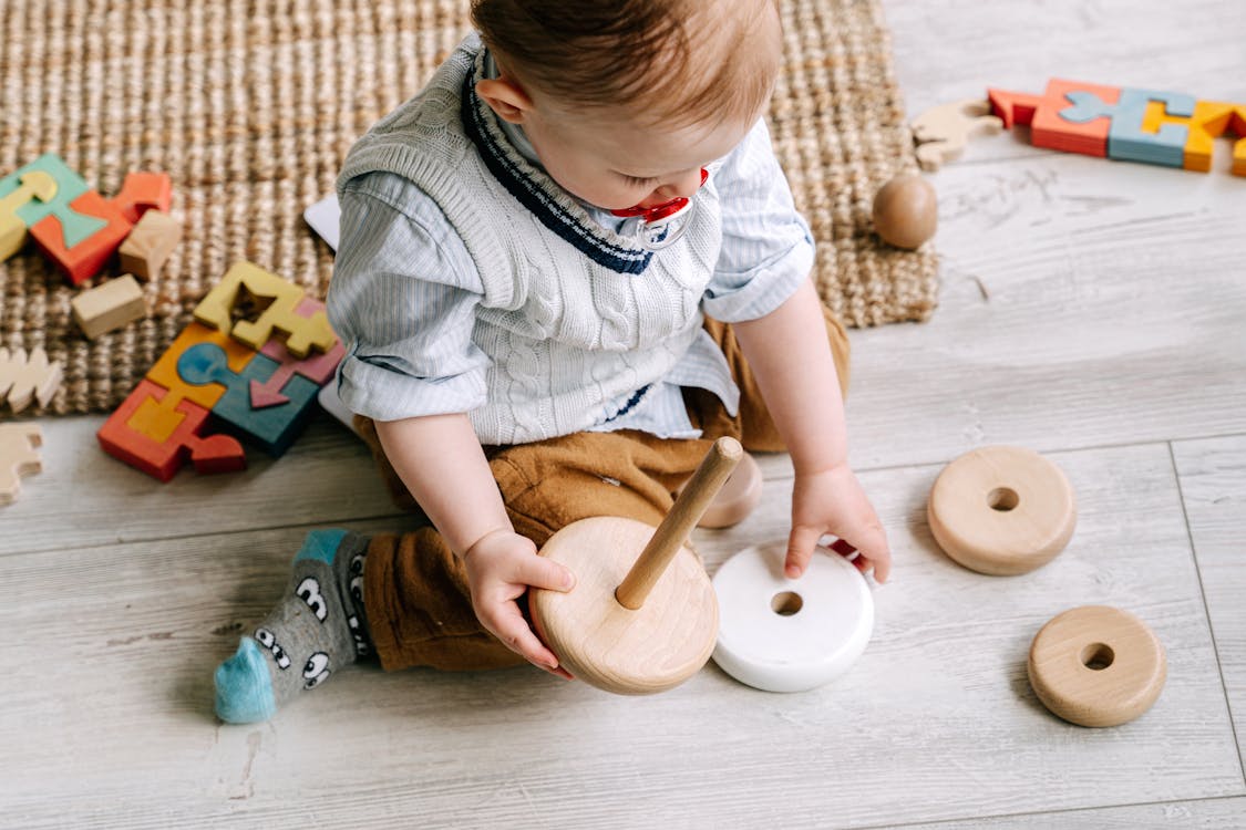 Free Baby Boy Playing with Wooden Toy on Floor Stock Photo