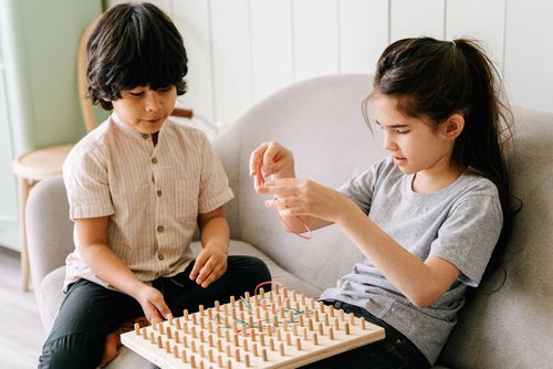 Free Two children engaged in a creative wooden board game indoors, fostering teamwork and learning. Stock Photo