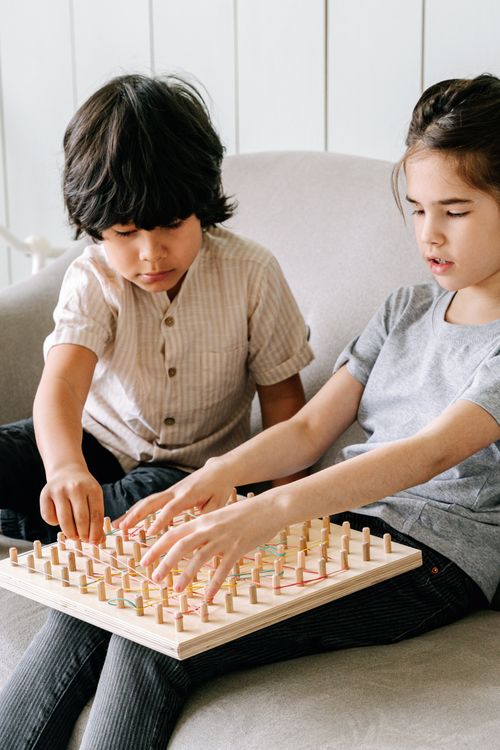 Free Two kids engaged in a fun strategy board game indoors on a cozy sofa. Stock Photo