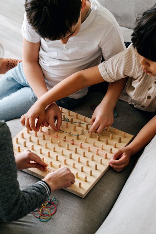 Free Children focus on assembling a wooden puzzle, enhancing learning and fun. Stock Photo