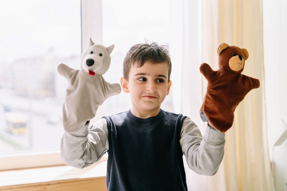 Boy playing with bear hand puppets on his hands
