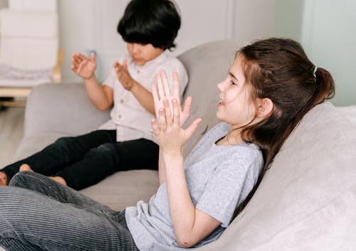 Two Happy Kids Sitting on Couch while Clapping