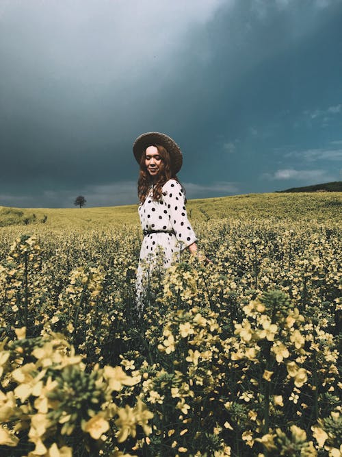 Woman in White Polka Dot Dress Standing on the Flower Field 