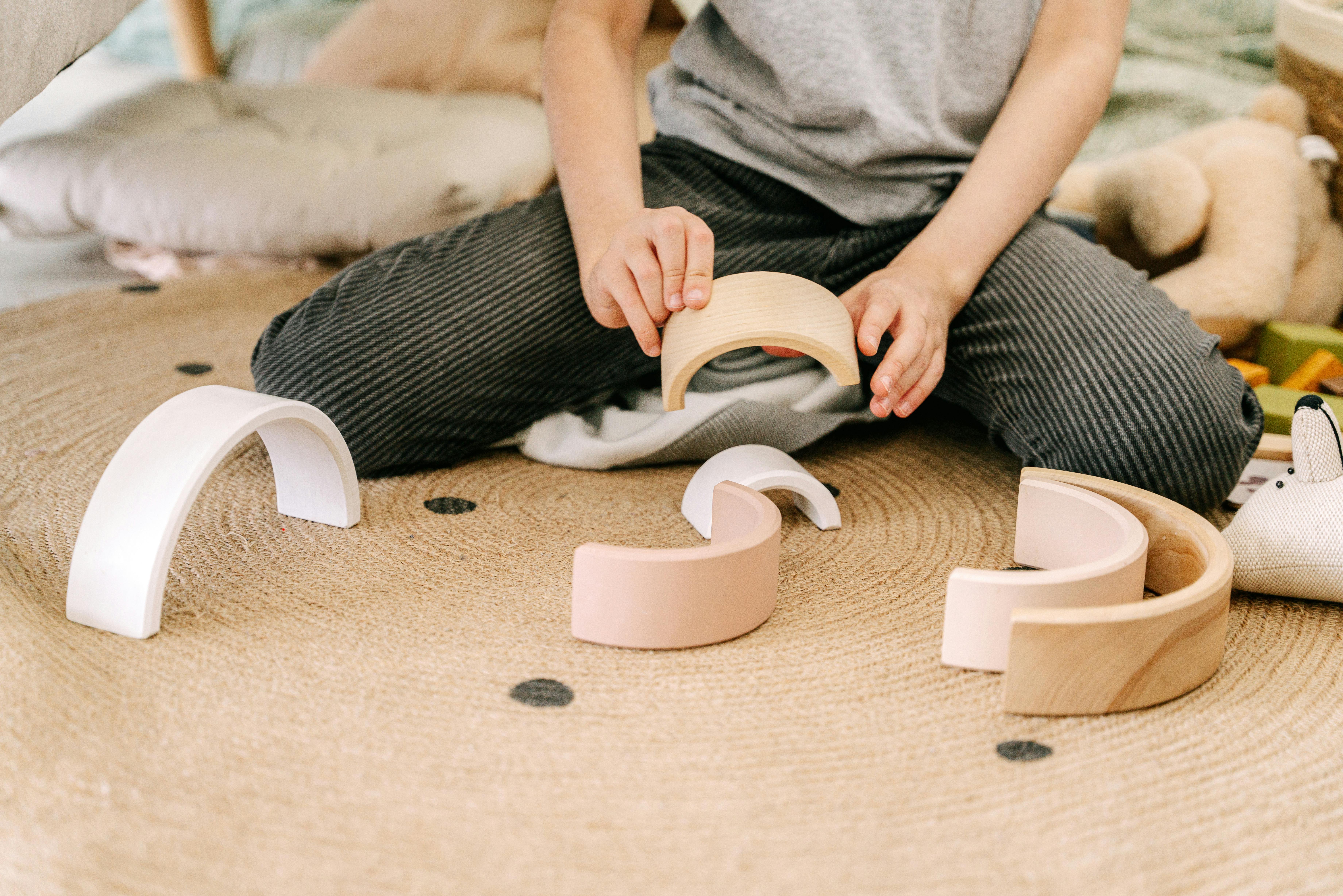 Close-Up Photo of a Kid Playing with Curved Wooden Blocks