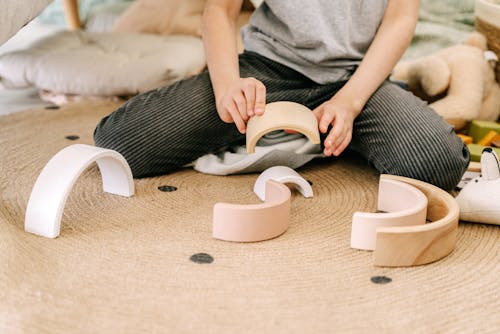 Close-Up Photo of a Kid Playing with Curved Wooden Blocks