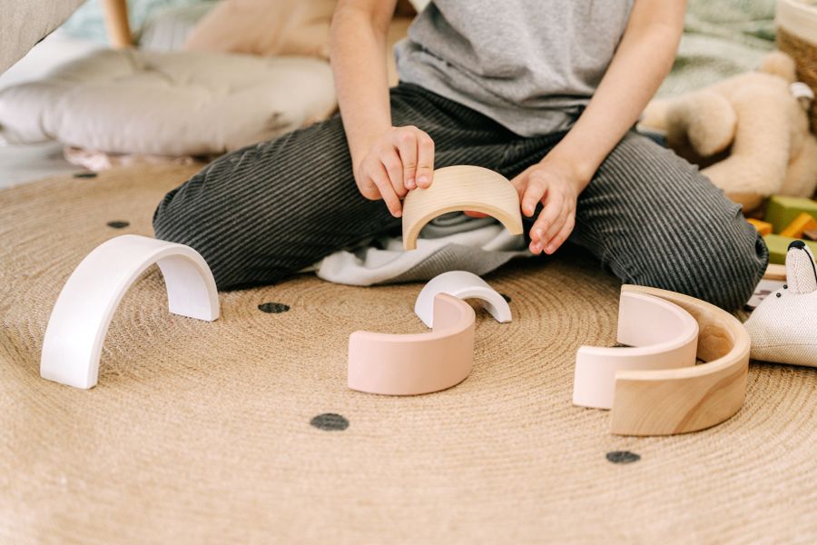 Child's hands arranging a wooden rainbow stacker toy