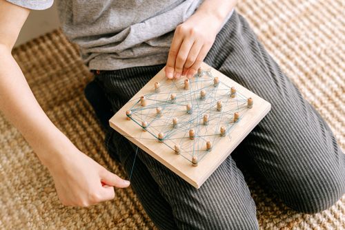 Free Child using a geoboard with blue threads for a creative and mindful activity. Stock Photo