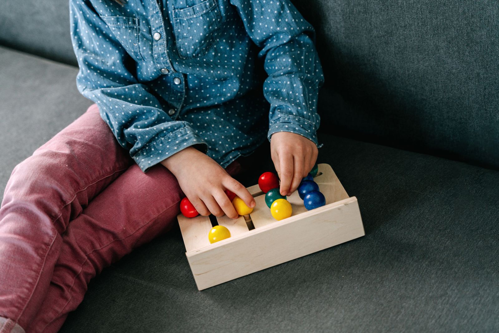 Child carefully fitting colorful shapes into a wooden puzzle