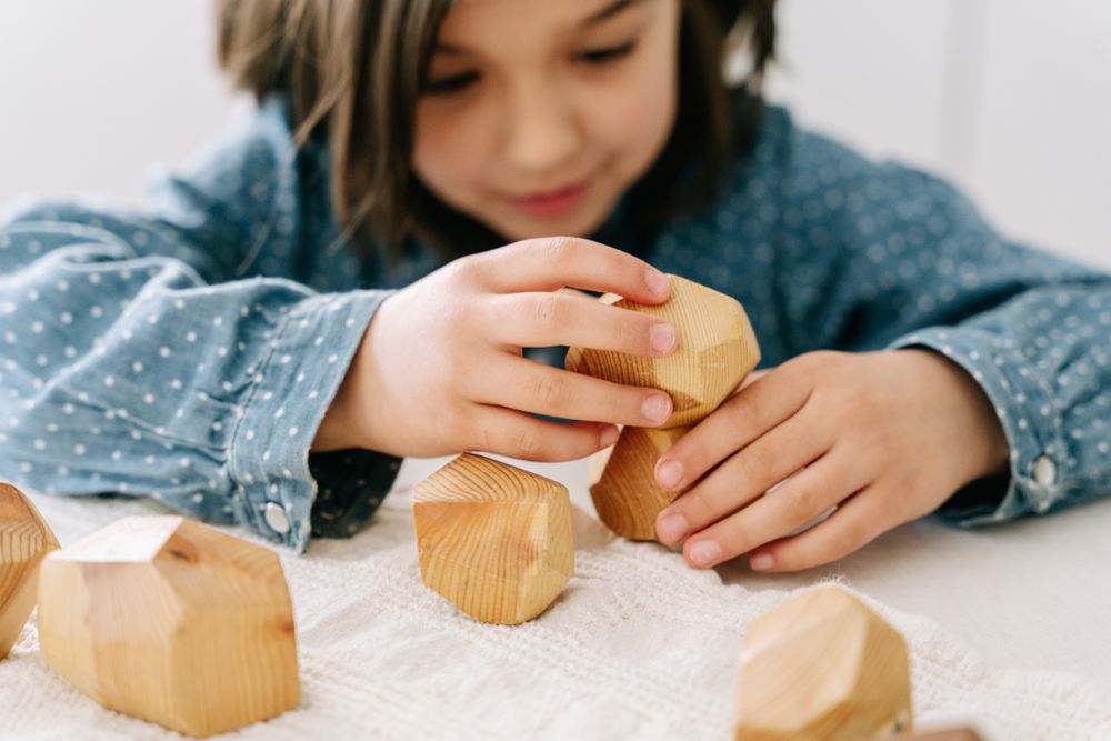 Child concentrating while building with wooden blocks