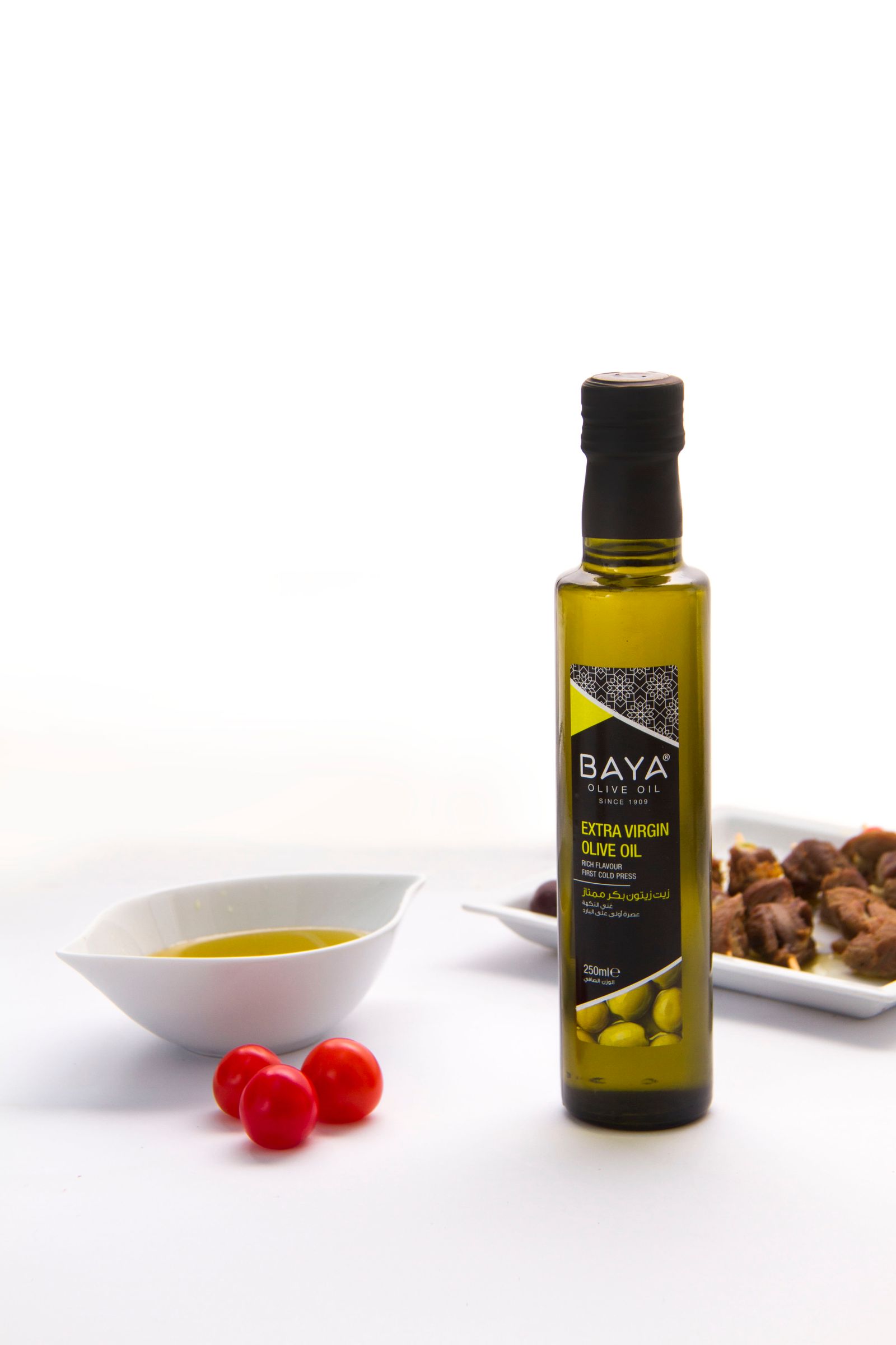 Green glass bottle of olive oil on a clean white surface.