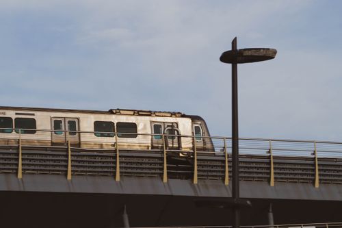 Free A train travels on an elevated railway under a clear blue sky, symbolizing modern transportation. Stock Photo