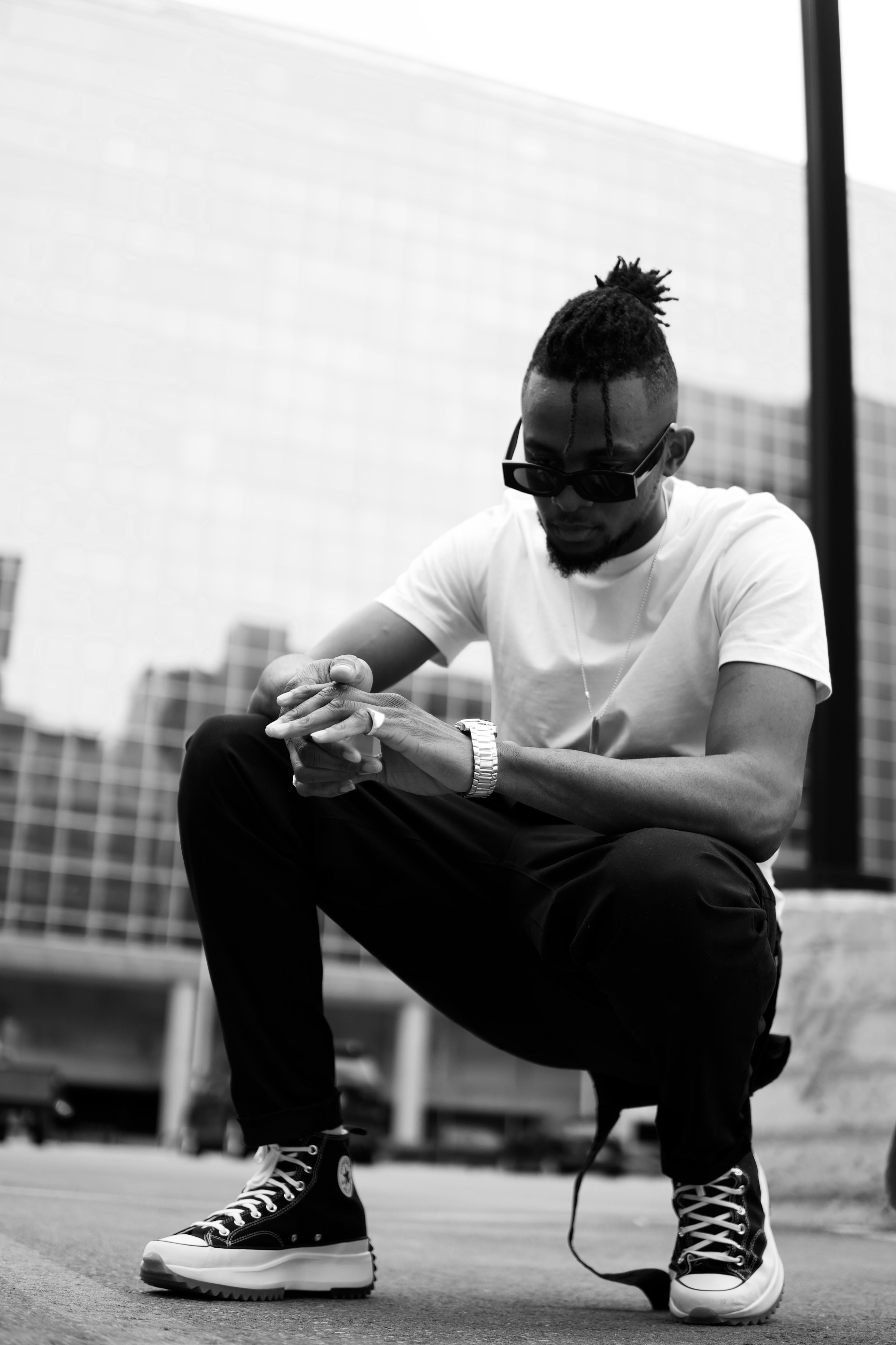 Black and white photo of a man in streetwear fashion posing in an urban Canadian setting.