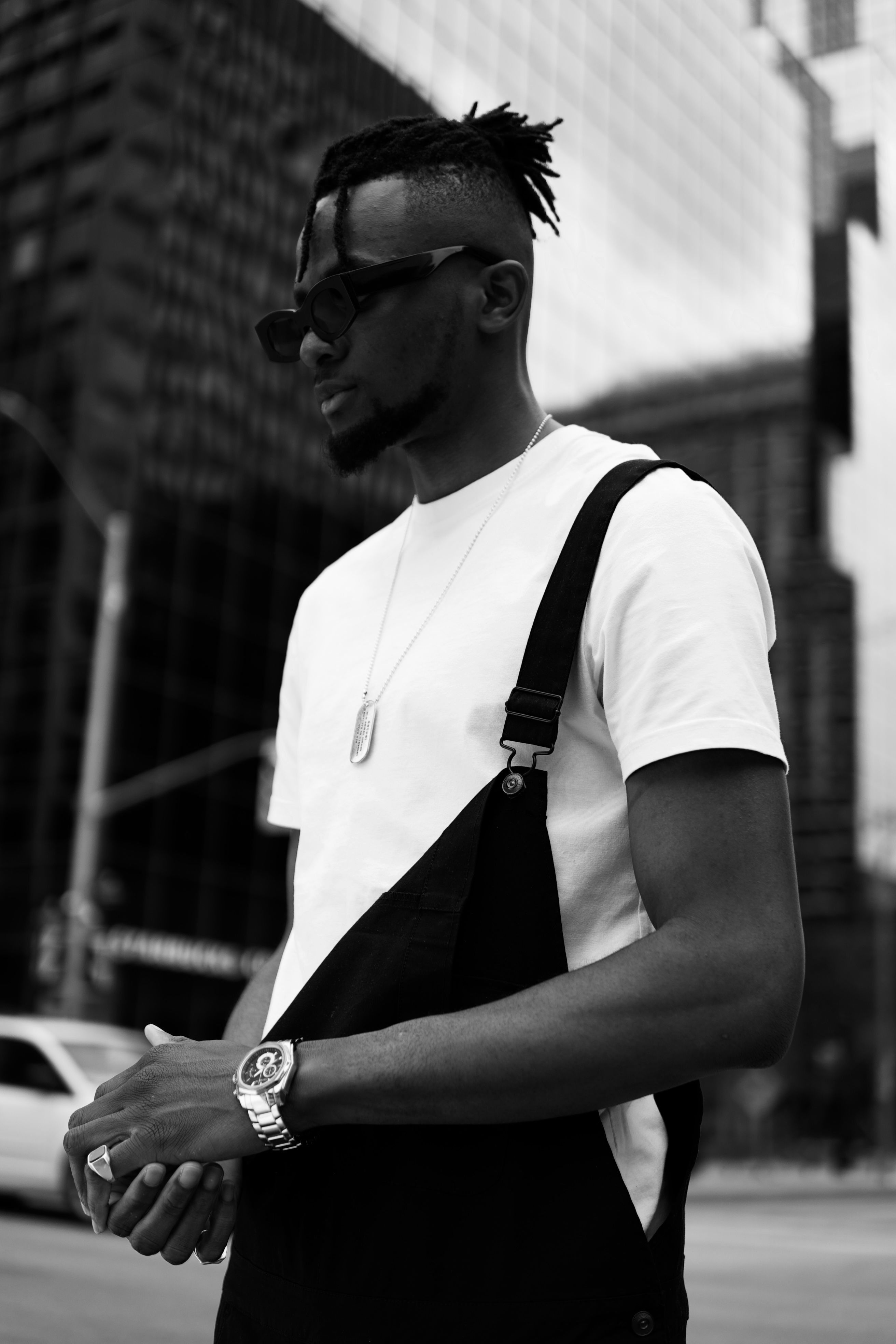 Stylish man in sunglasses and streetwear posing in Canadian city in grayscale.