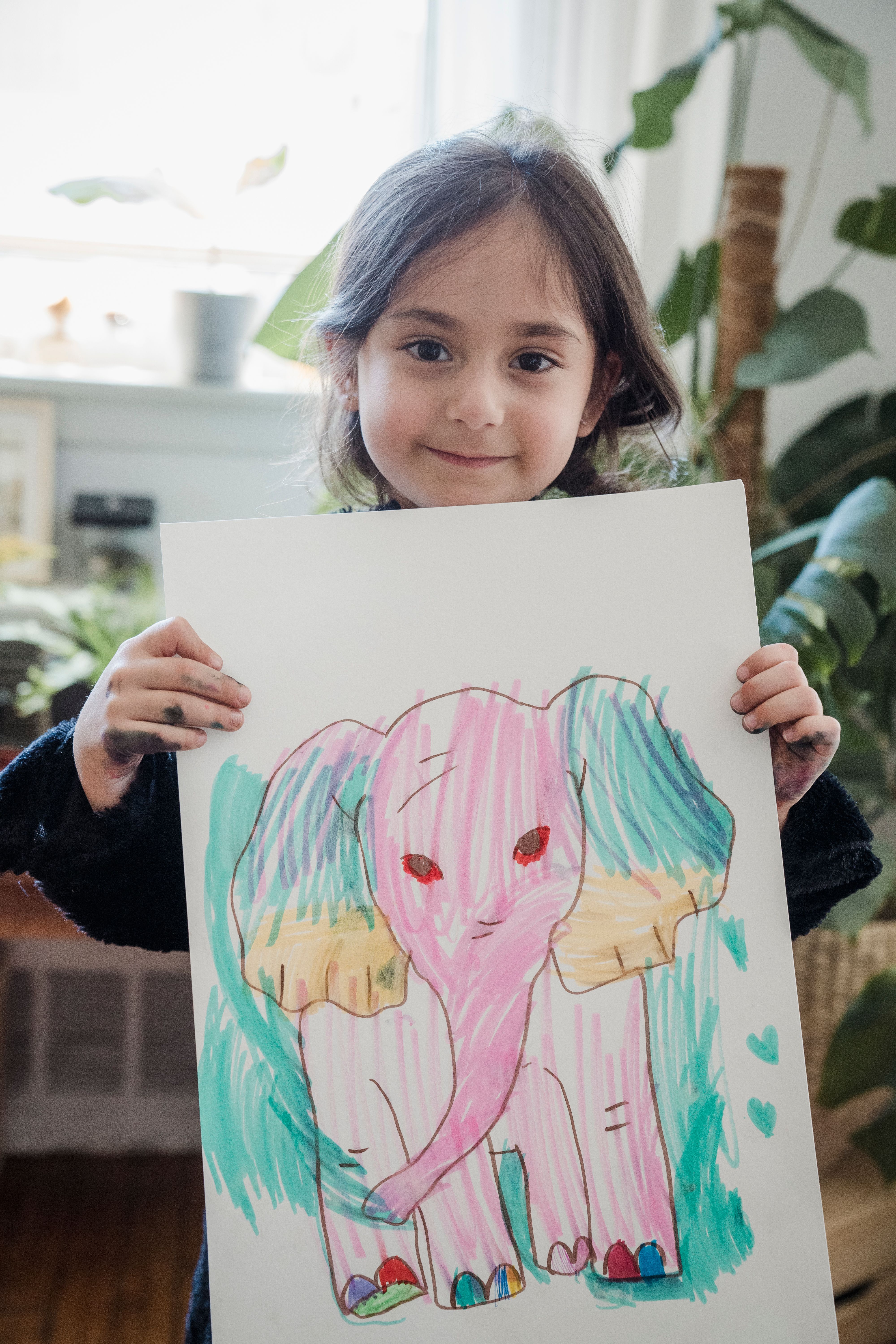 A person proudly displaying their finished packing peanut portrait of a celebrity, smiling at the camera