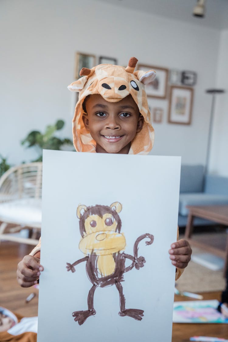 A Young Boy Holding A White Paper With Monkey Drawing