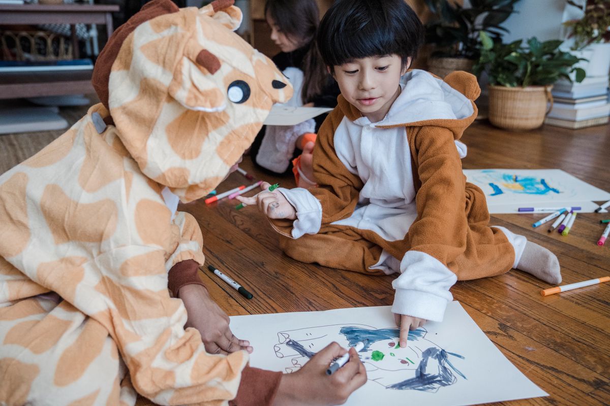 Kids in animal onesies creating imaginative drawings of a unicorn pony indoors
