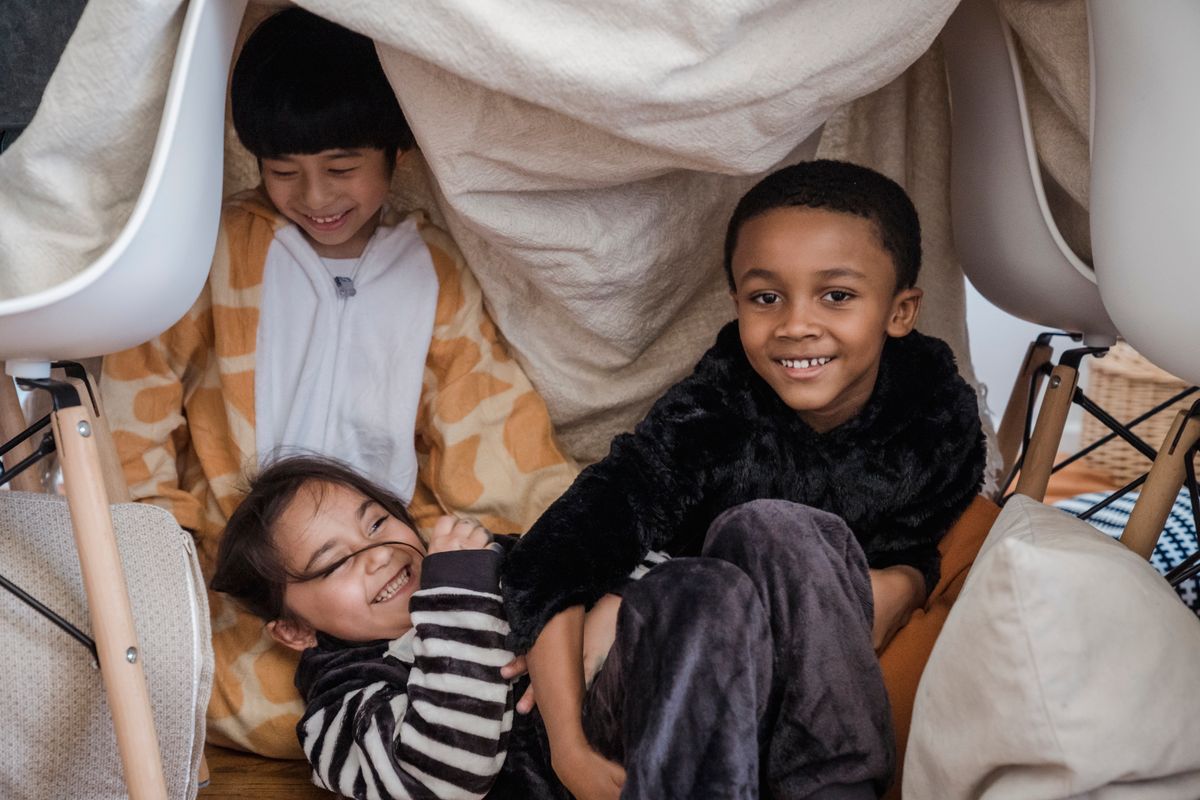 Kids playing in a blanket fort in the living room