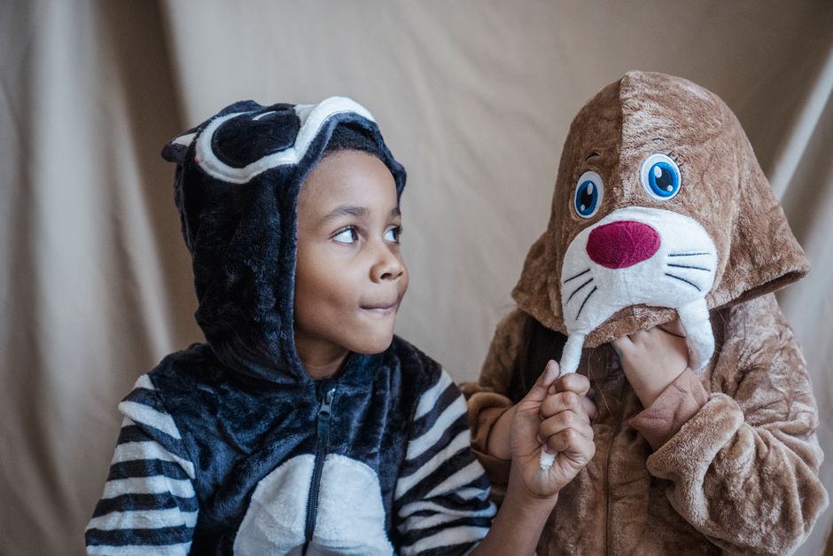 Two children wearing animal costumes engage in playful interaction indoors, adding whimsy to childhood moments.