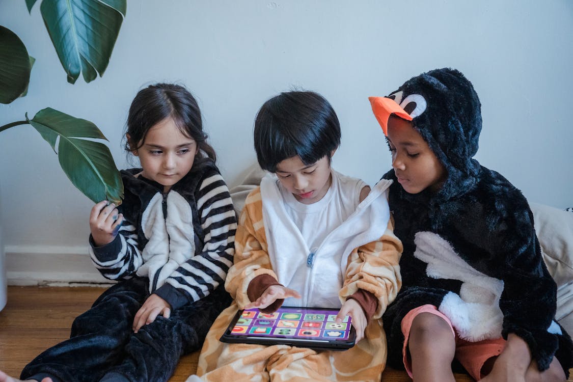 Free Kids in Costumes Playing Games with Tablet Computer Stock Photo
