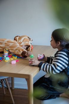 Two children playing with colorful toys on a wooden table indoors. Fun and creativity in costumes.