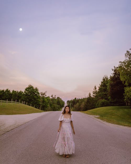 Woman in White Dress Standing on the Road During Sunset
