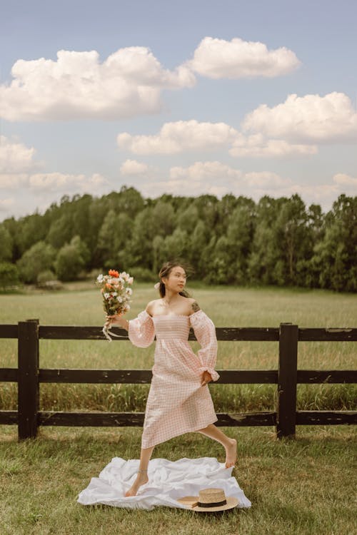 Woman in the Grass Field Holding Bouquet of Flower
