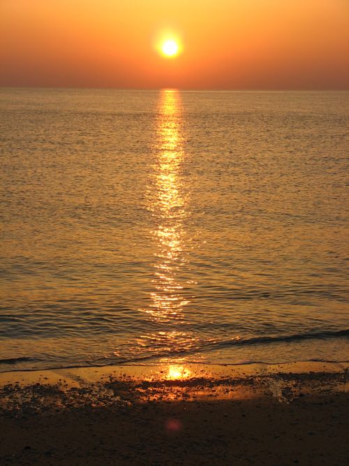 Free Beautiful golden sunset reflecting over calm ocean waters creating a tranquil seascape. Stock Photo
