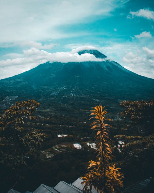 Free A stunning view of a mountain surrounded by clouds and vibrant greenery. Stock Photo