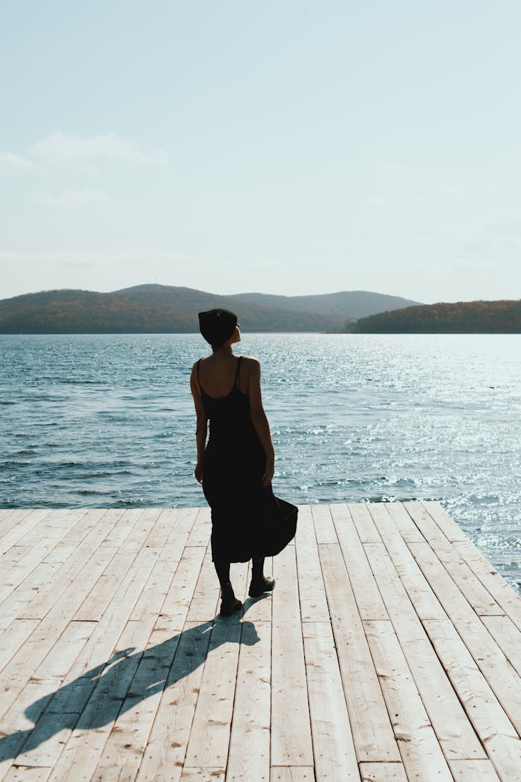 Woman In Black Dress Standing On Deck Near The Beach