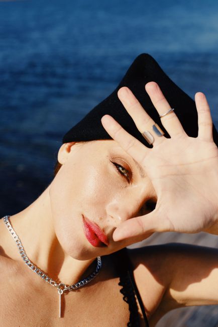 Portrait of a woman shielding her eyes from the sun by the sea.