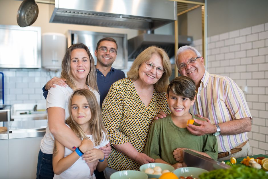 Familia feliz de seis disfrutando del tiempo juntos en una cocina moderna.